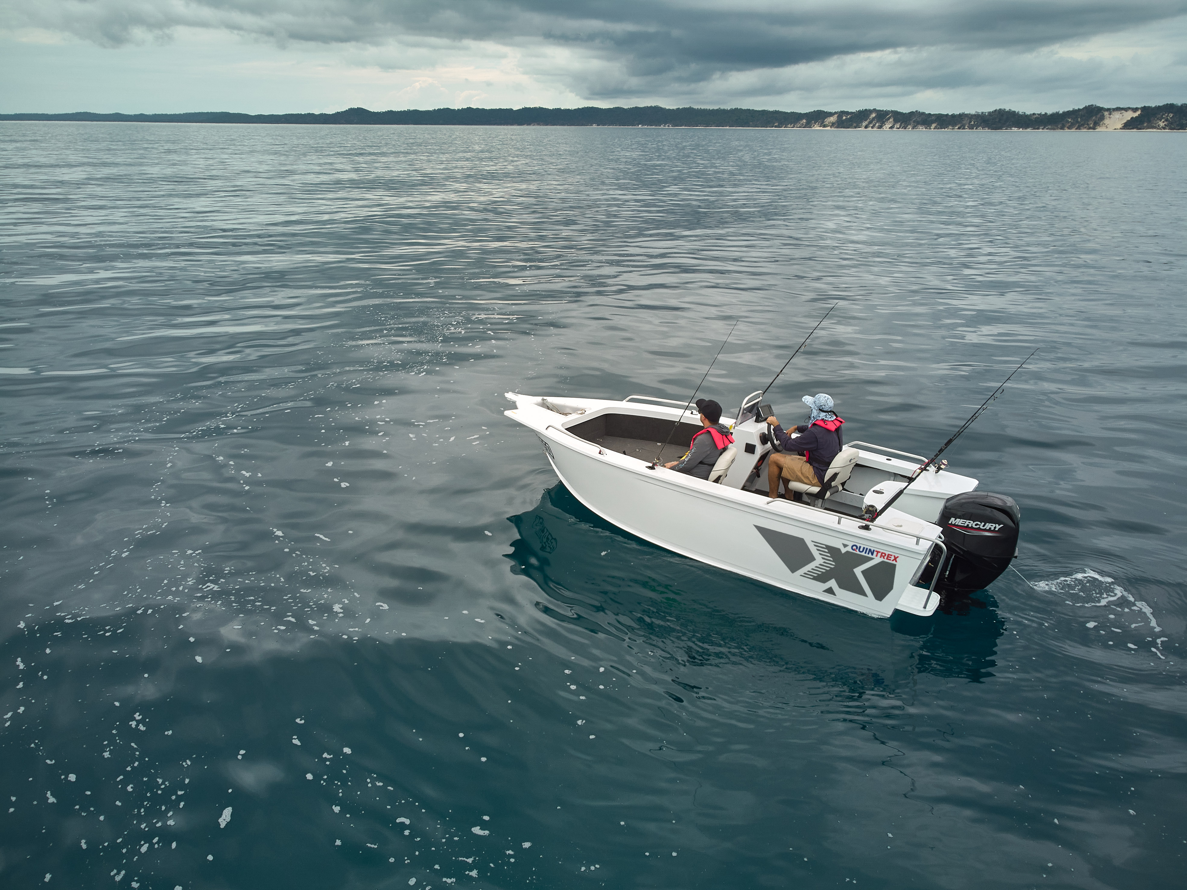 A white Quintrex Renegade side console under way in clear coastal water with two anglers aboard