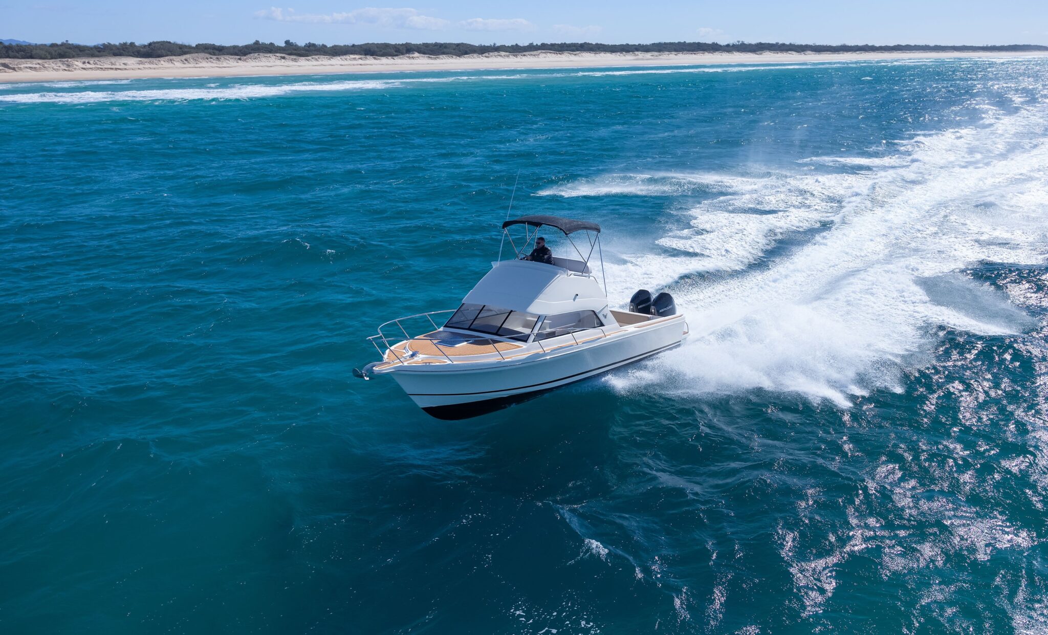 Caribbean 27F Flybridge running on the water, twin outboards visible astern